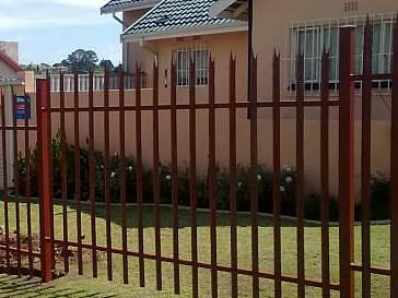 Red powder coated palisade fencing around the houses.